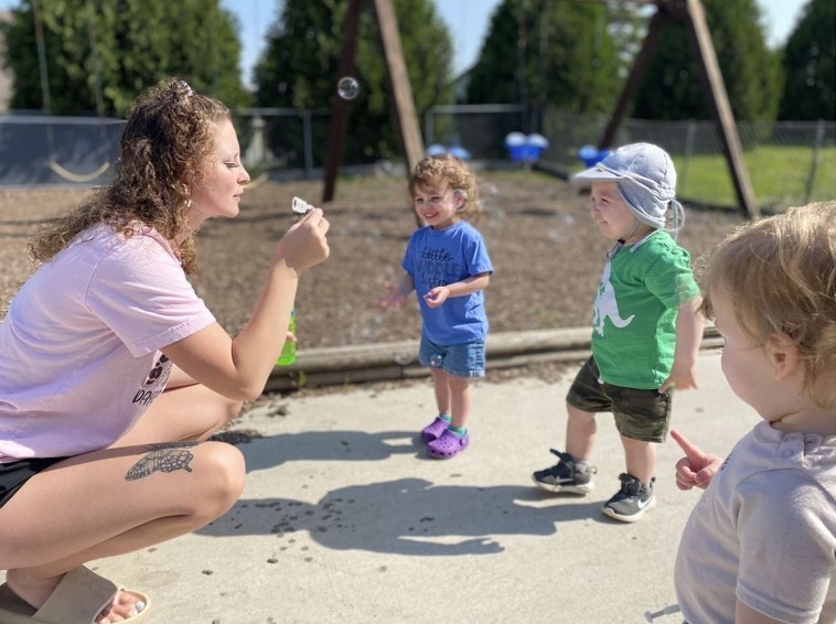 a daycare worker blowing bubbles with children