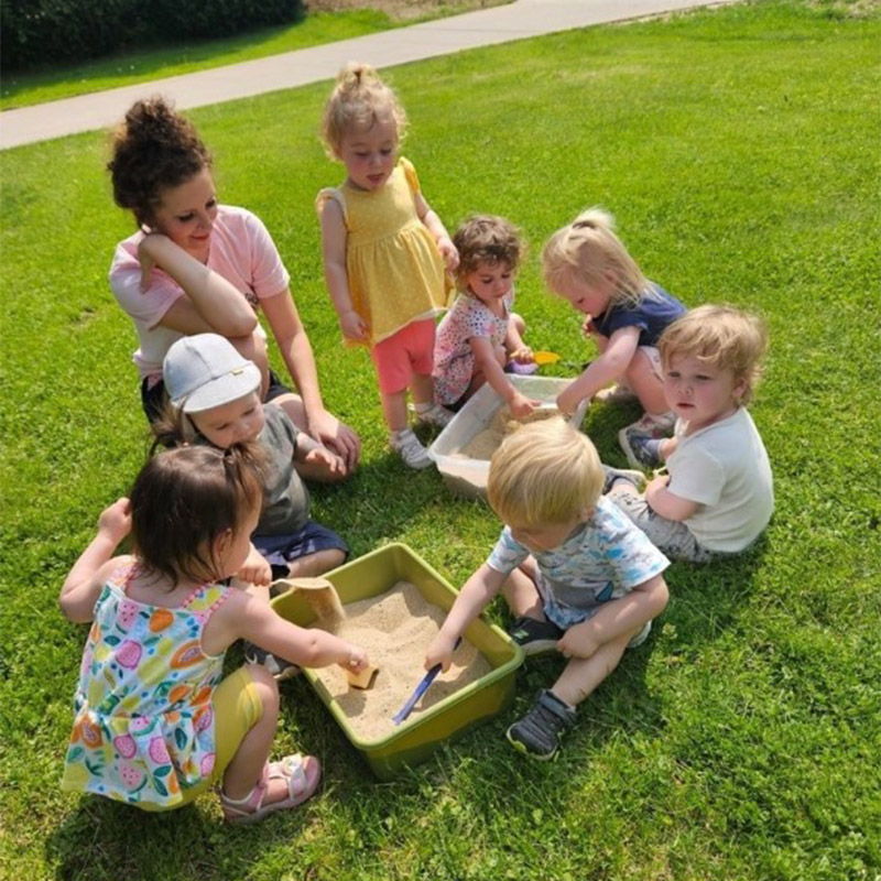 toddlers playing outside with a daycare worker