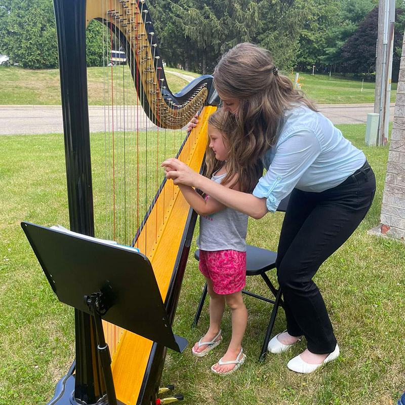 a small girl learning how to play a harp